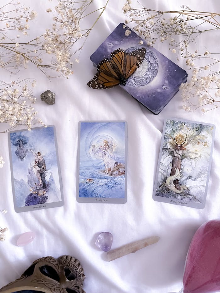 Stunning tarot card layout on white cloth with crystals and butterfly for divination.